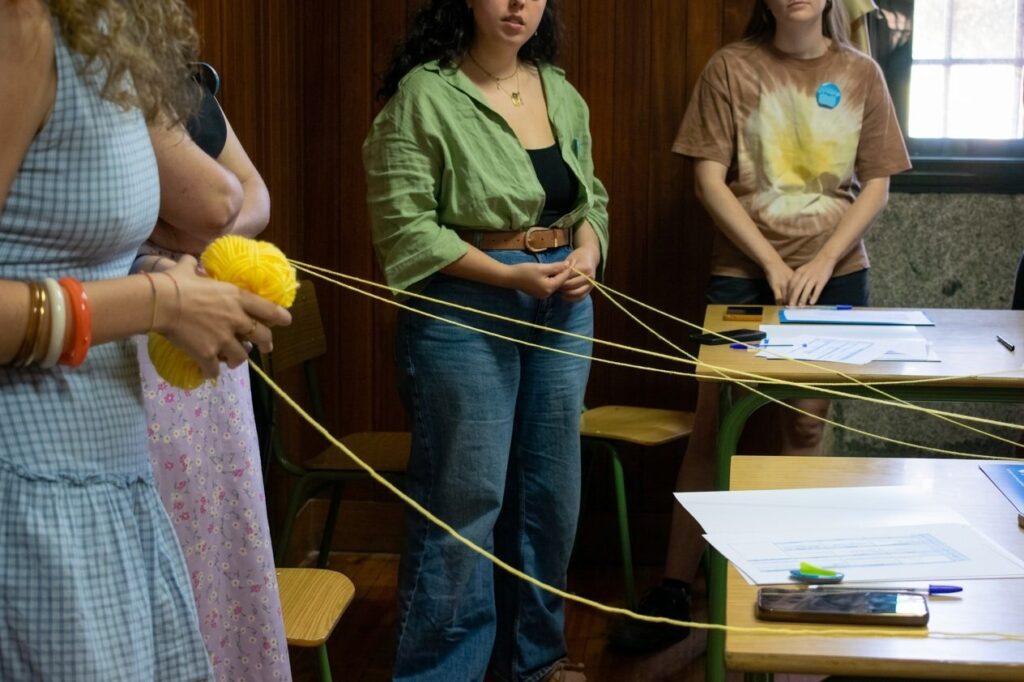 Participantes de CanteirIA forman una red con un ovillo de lana amarilla durante la dinámica de presentación